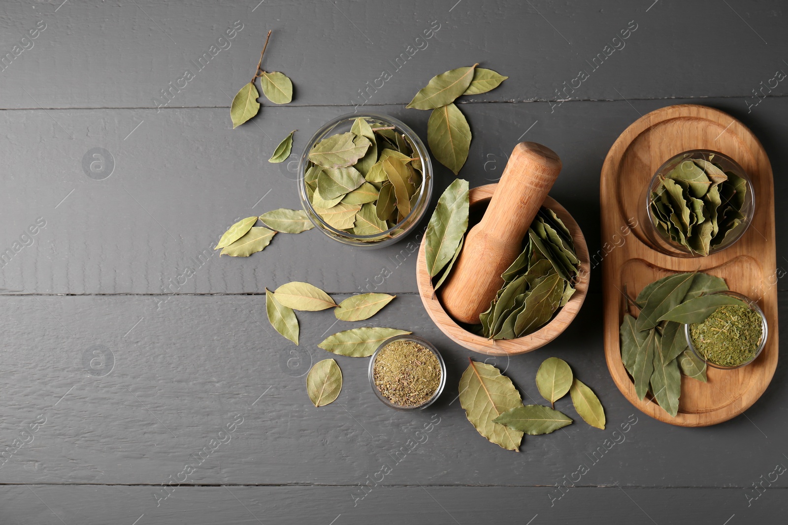 Photo of Whole and ground bay leaves on grey wooden table, flat lay. Space for text