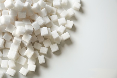 Photo of Refined sugar cubes on light background