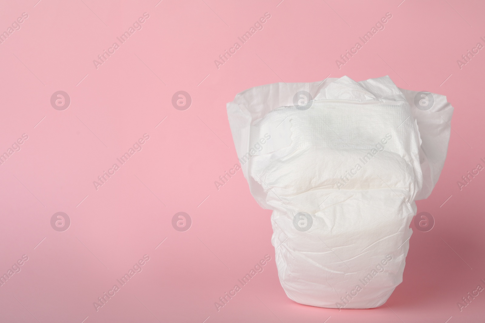 Photo of Baby diaper on pink background. Space for text