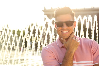 Photo of Handsome man wearing stylish sunglasses on city street. Space for text