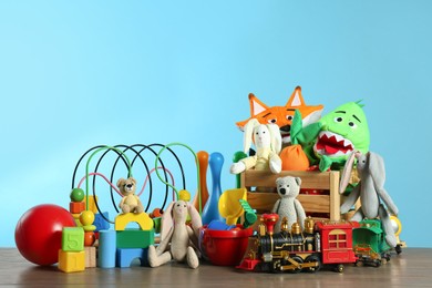 Photo of Many different toys on wooden table against light blue background