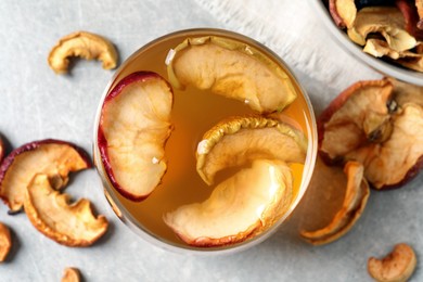 Delicious compote with dried apple slices in glass on grey table, flat lay