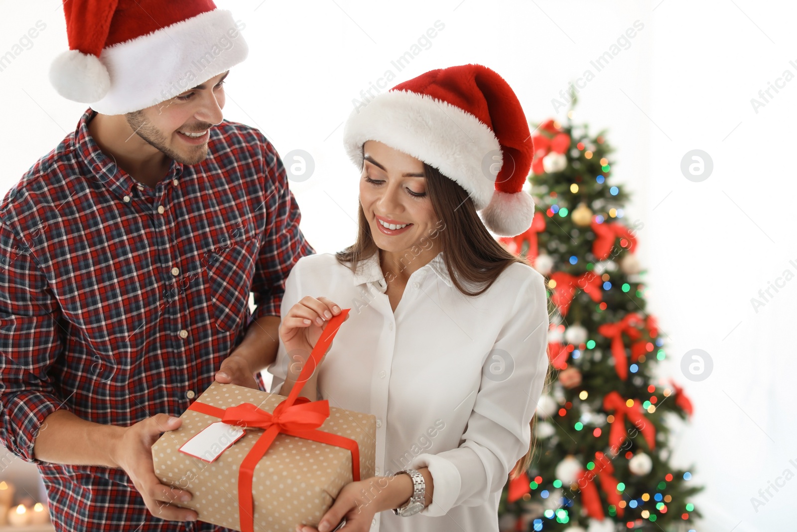 Photo of Young couple with Christmas gift at home