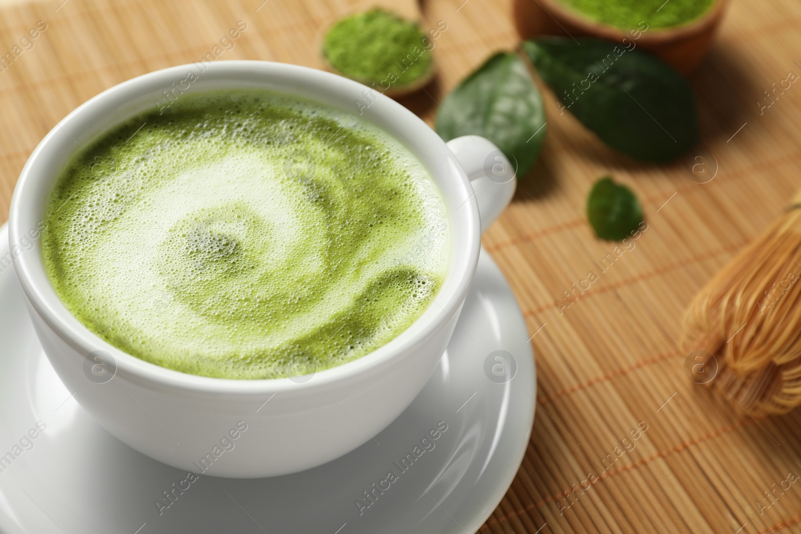 Photo of Delicious matcha latte in cup on bamboo mat, closeup. Space for text