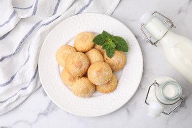 Photo of Tasty sweet sugar cookies, milk and mint on white marble table, top view