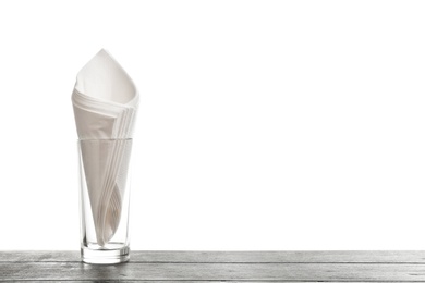 Glass with paper napkins on table against white background. Space for text