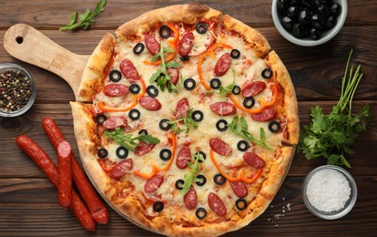 Tasty pizza and ingredients on wooden table, top view