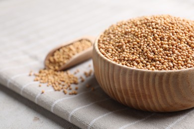 Photo of Mustard seeds in wooden bowl on table, closeup. Space for text