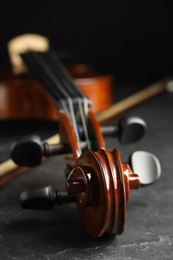Photo of Classic violin and bow on grey stone table, closeup