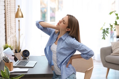 Photo of Young woman suffering from back pain in office