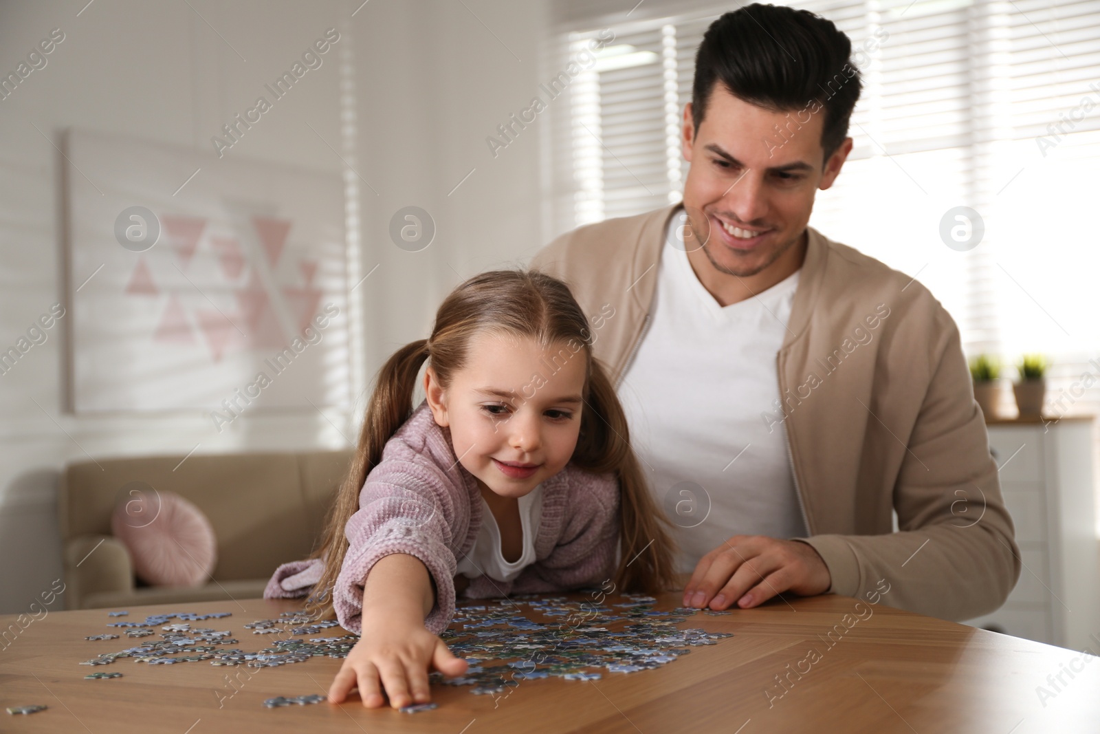 Photo of Man and his little daughter playing with puzzles at home