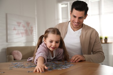 Man and his little daughter playing with puzzles at home