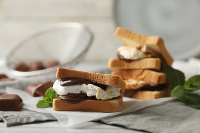 Delicious marshmallow sandwich with bread and chocolate on white wooden table, closeup
