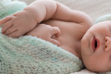 Cute newborn baby in warm hat sleeping on white plaid, closeup