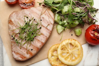 Photo of Delicious tuna steak, salad, tomato and lemon on board, flat lay