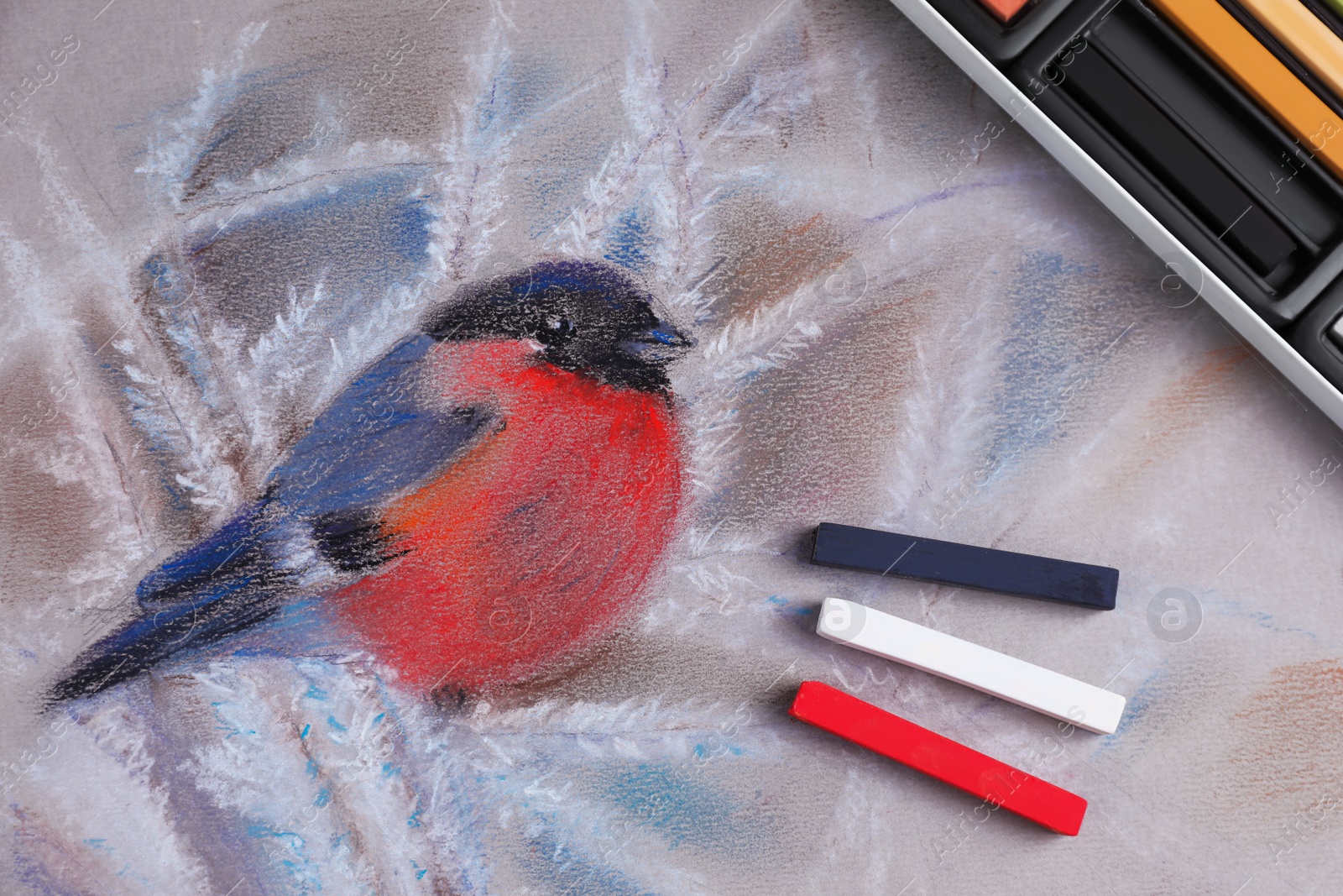 Photo of Colorful chalk pastels on beautiful painting of bullfinch, flat lay