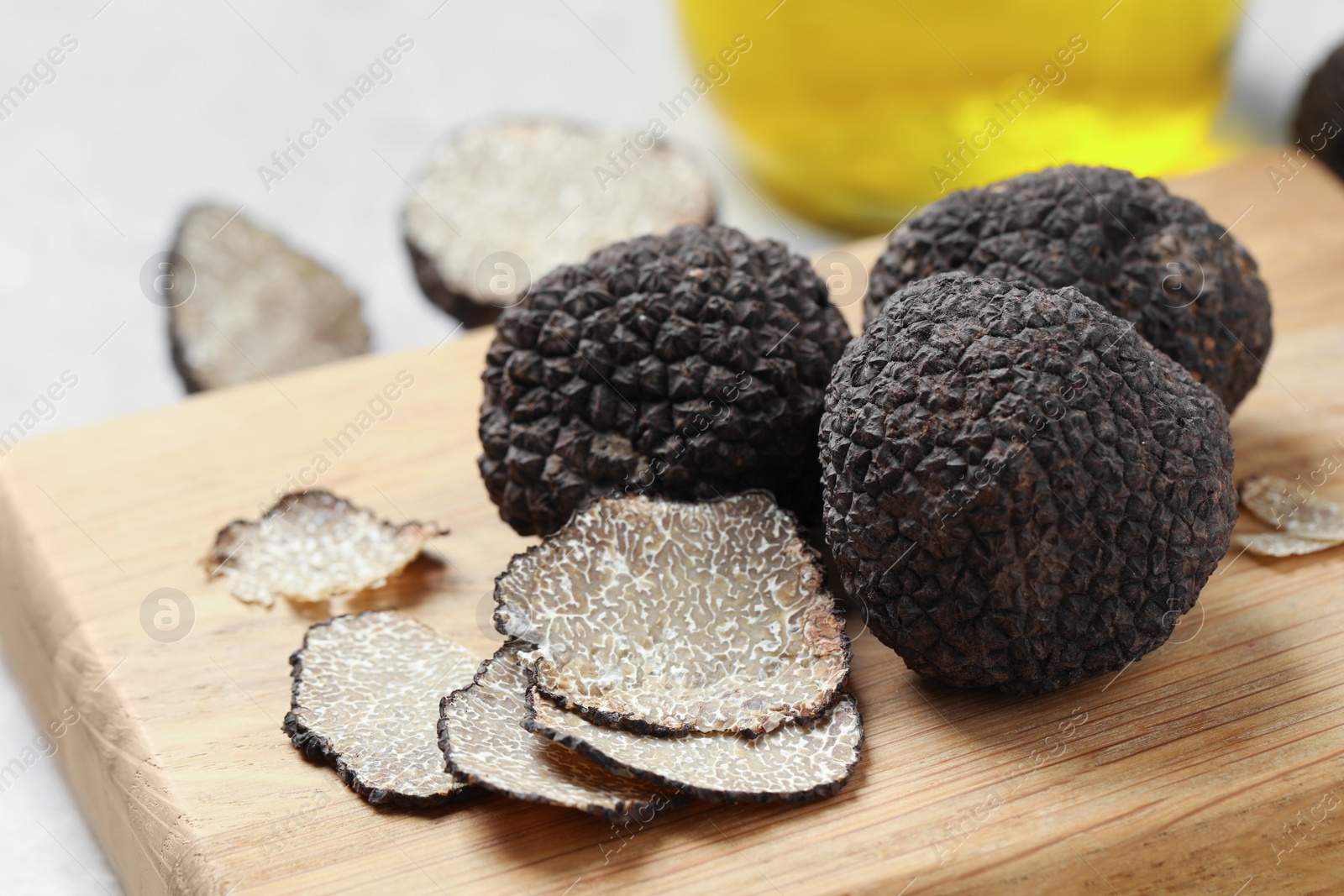 Photo of Black truffles with wooden board on table, closeup