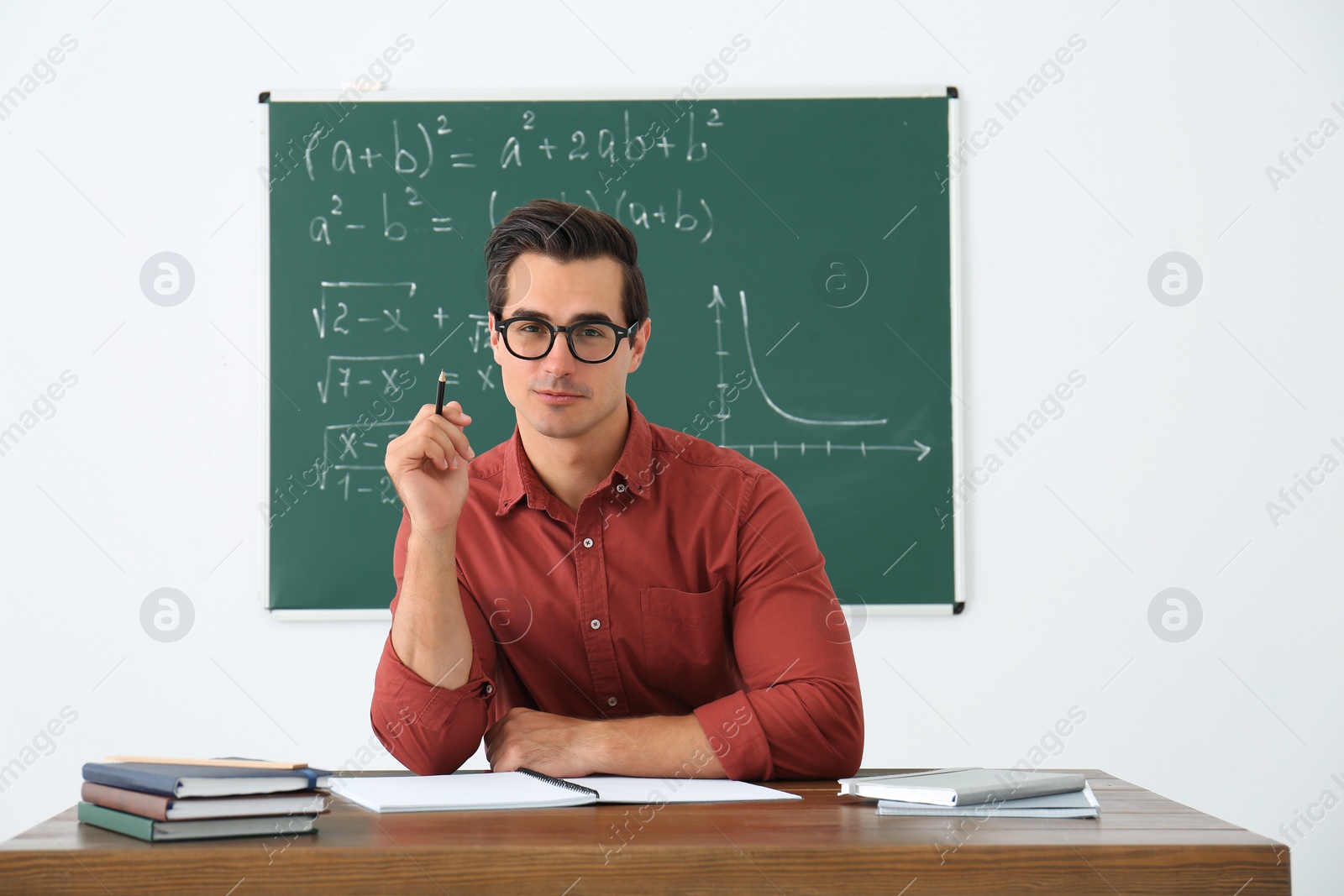 Photo of Young teacher working at table in classroom