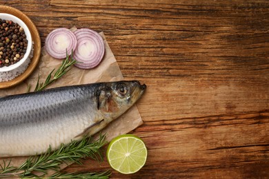 Photo of Delicious salted herring and ingredients on wooden table, flat lay. Space for text
