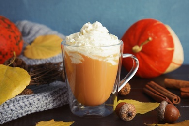 Photo of Composition with tasty pumpkin spice latte in glass cup on table