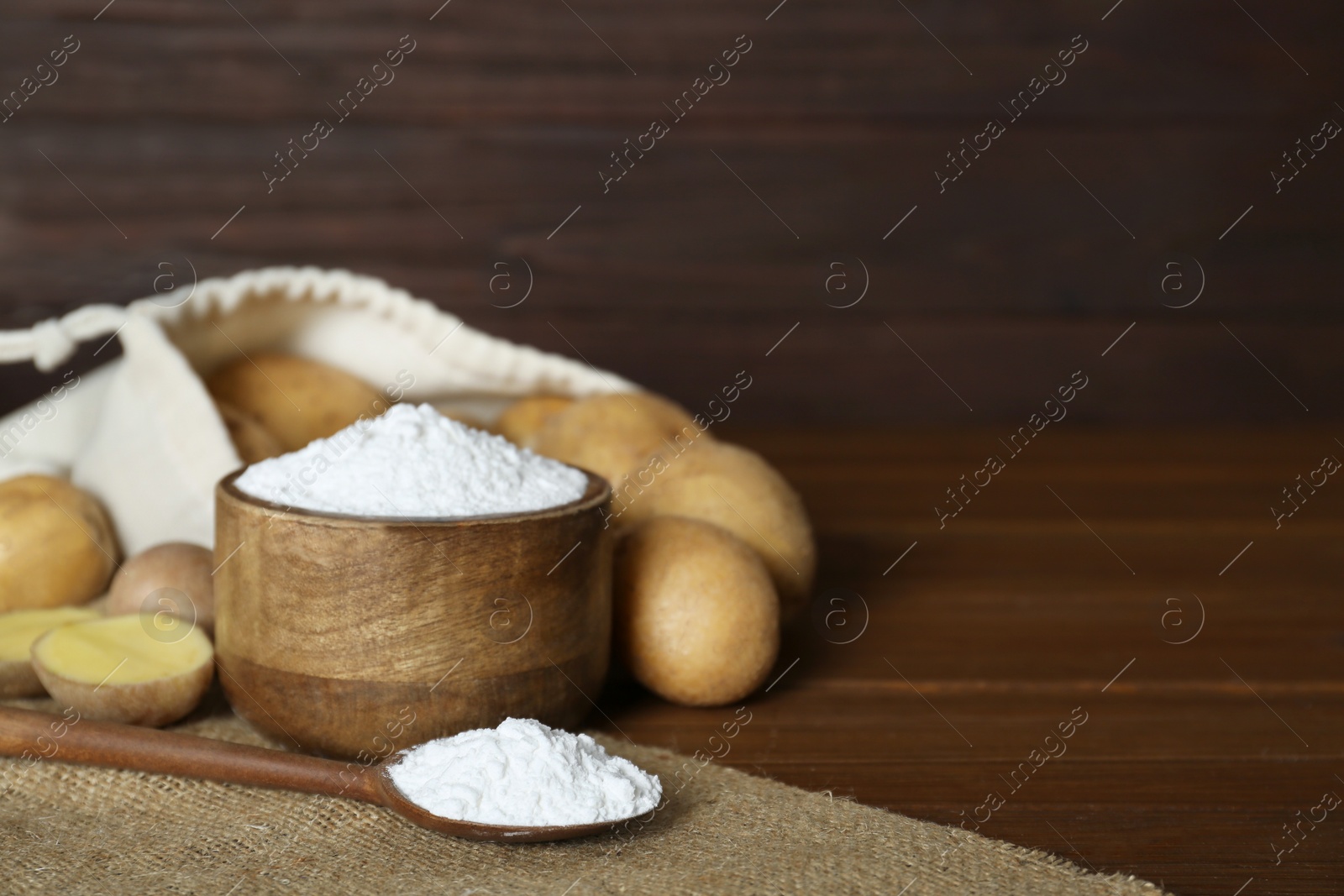 Photo of Starch and fresh raw potatoes on wooden table. Space for text