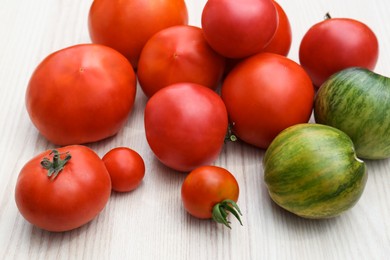 Many different ripe tomatoes on white wooden table