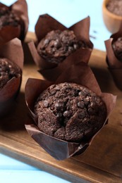 Tasty chocolate muffins on light blue table, closeup