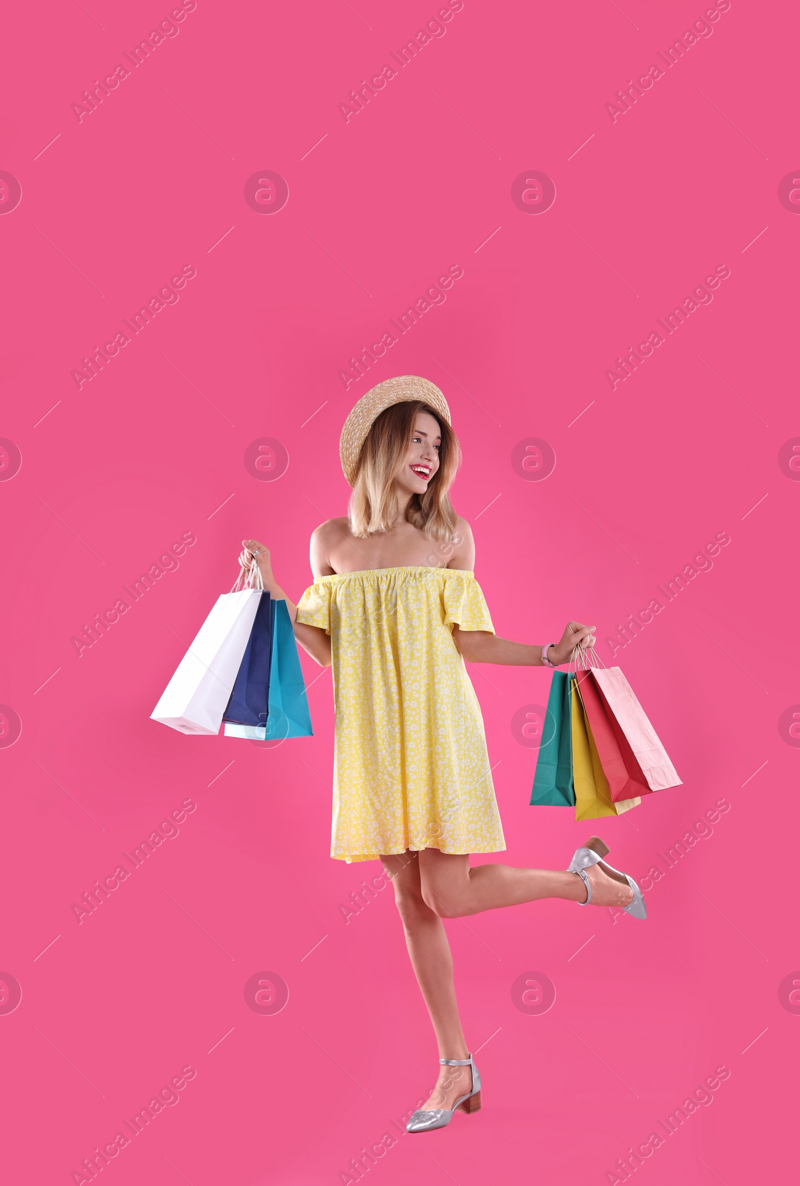 Photo of Beautiful young woman with shopping bags on color background