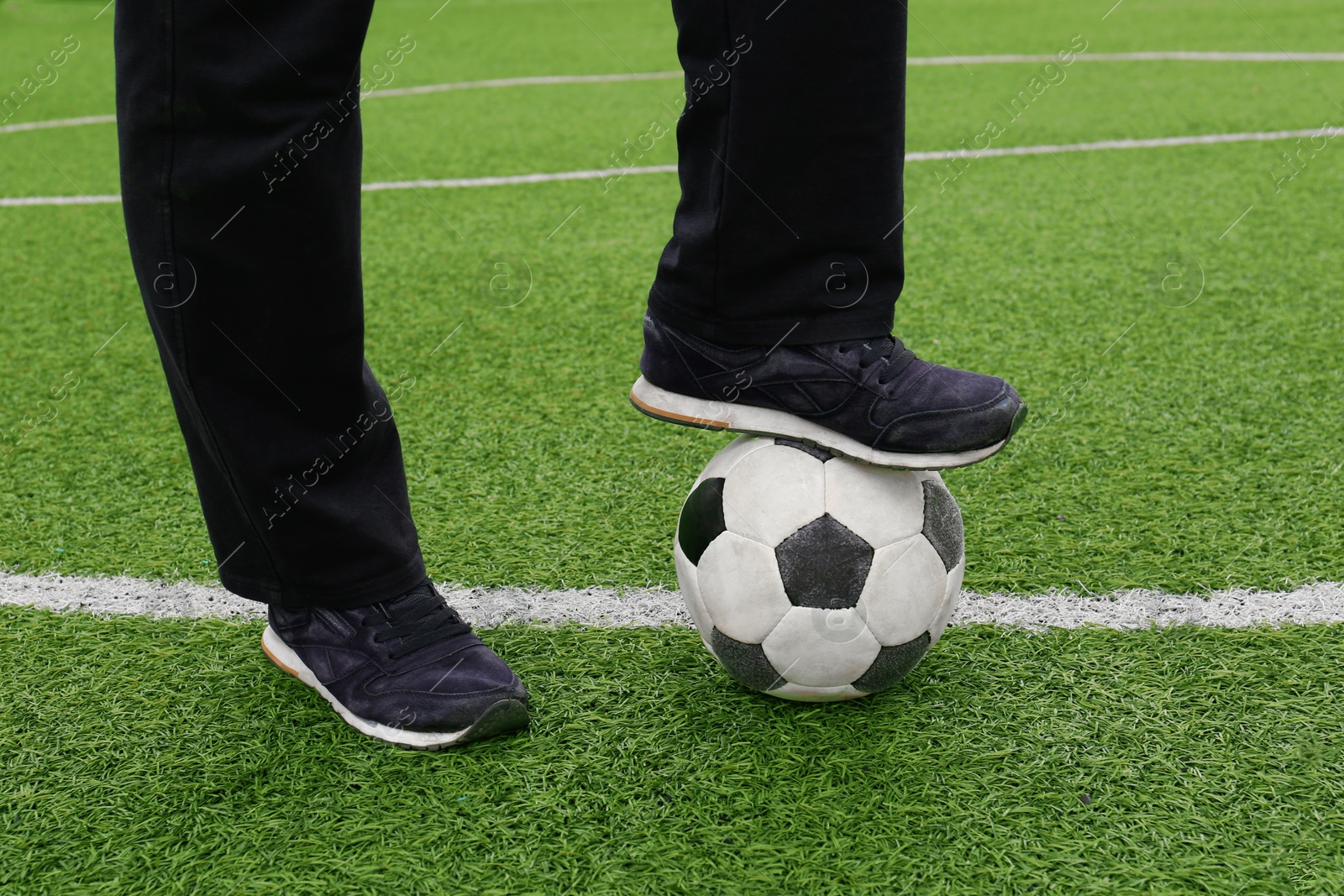 Photo of Man with soccer ball on green grass at stadium, closeup