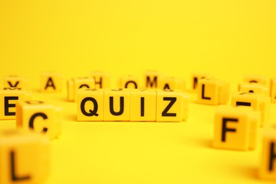 Photo of Cubes with word Quiz on yellow background. Space for text