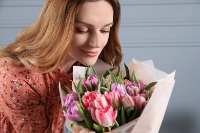 Photo of Happy young woman with bouquet of beautiful tulips indoors