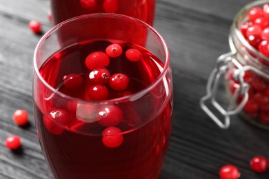 Tasty cranberry juice in glasses and fresh berries on black wooden table, closeup