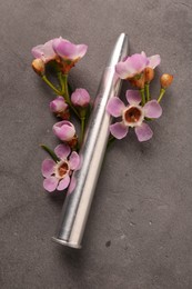 Metal bullet and beautiful flowers on grey textured table, above view