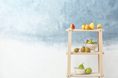 Photo of Shelving unit with ripe pears on color background. Space for text