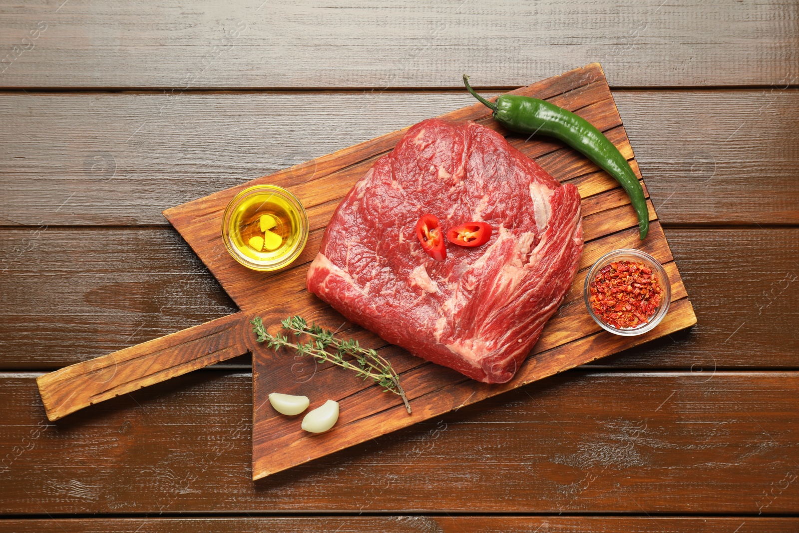 Photo of Fresh raw beef cut, spices and oil on wooden table, top view