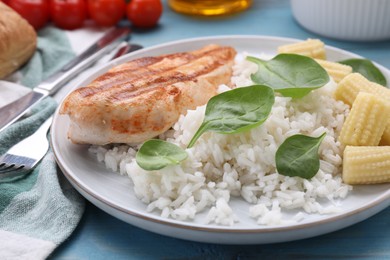 Grilled chicken breast and rice served with vegetables on light blue wooden table, closeup
