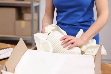 Post office worker packing parcel at table indoors, closeup