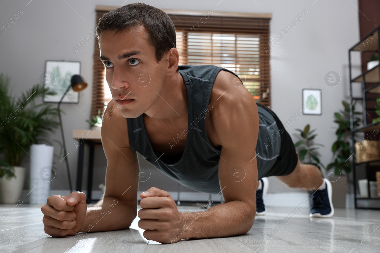 Photo of Handsome man doing plank exercise on floor at home