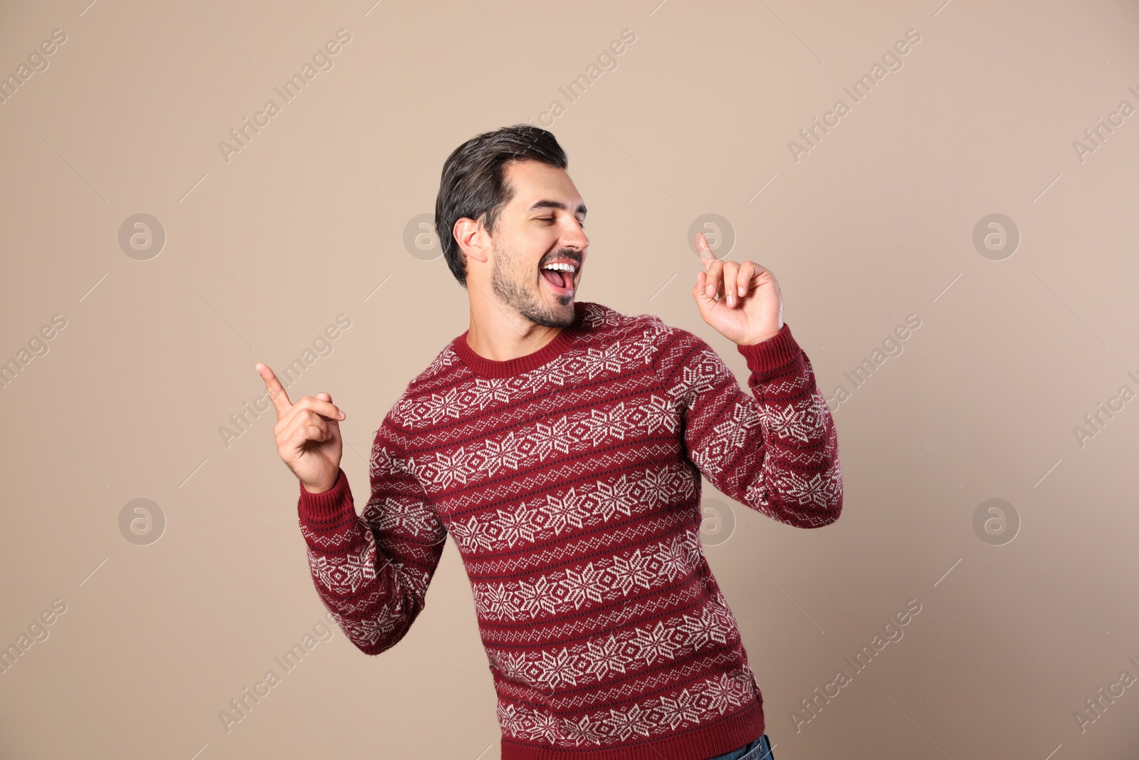 Photo of Happy young man in Christmas sweater on beige background