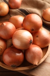 Photo of Many ripe onions on wooden table, closeup