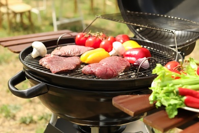 Photo of Modern grill with meat and vegetables outdoors, closeup