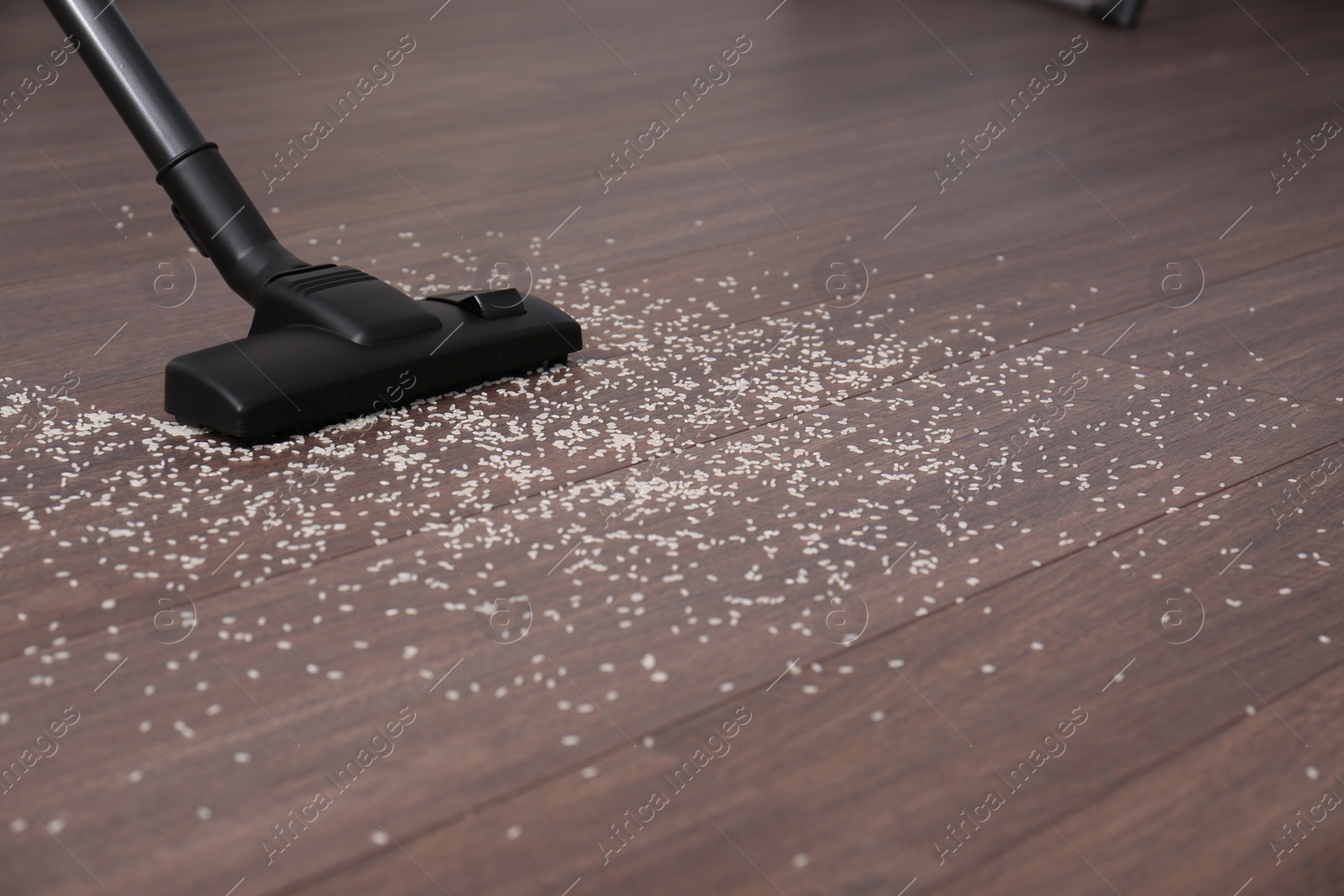 Photo of Vacuuming scattered rice from wooden floor. Space for text