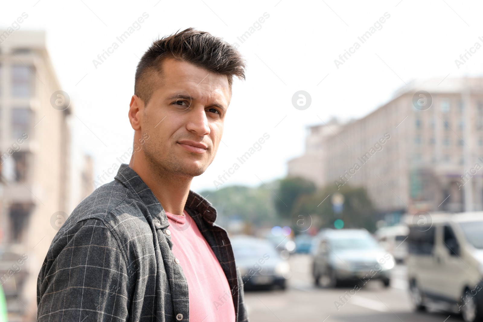 Photo of Portrait of handsome young man on city street. Space for text