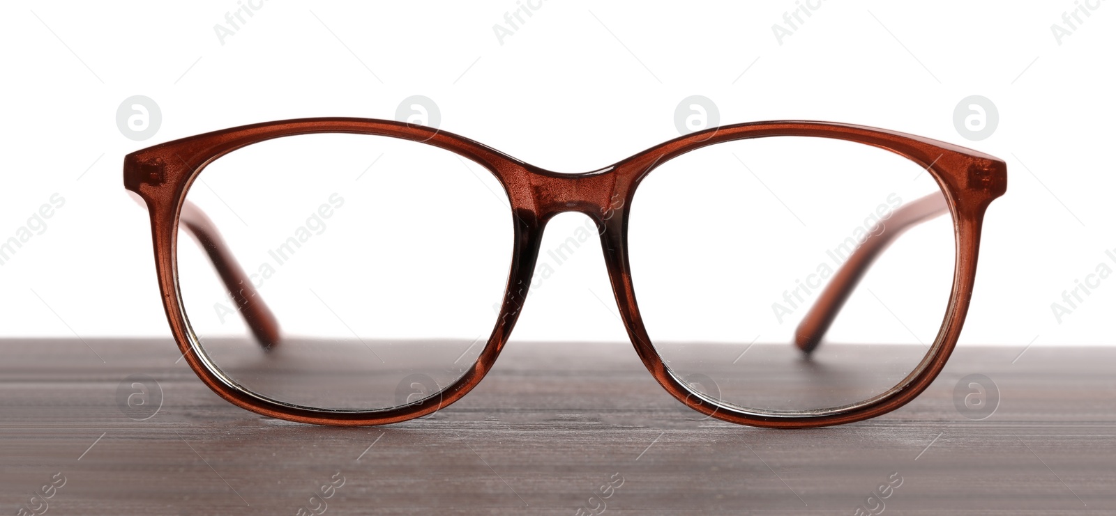 Photo of Stylish glasses with brown frame on wooden table against white background