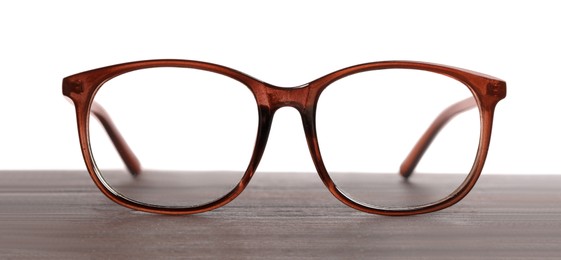 Photo of Stylish glasses with brown frame on wooden table against white background