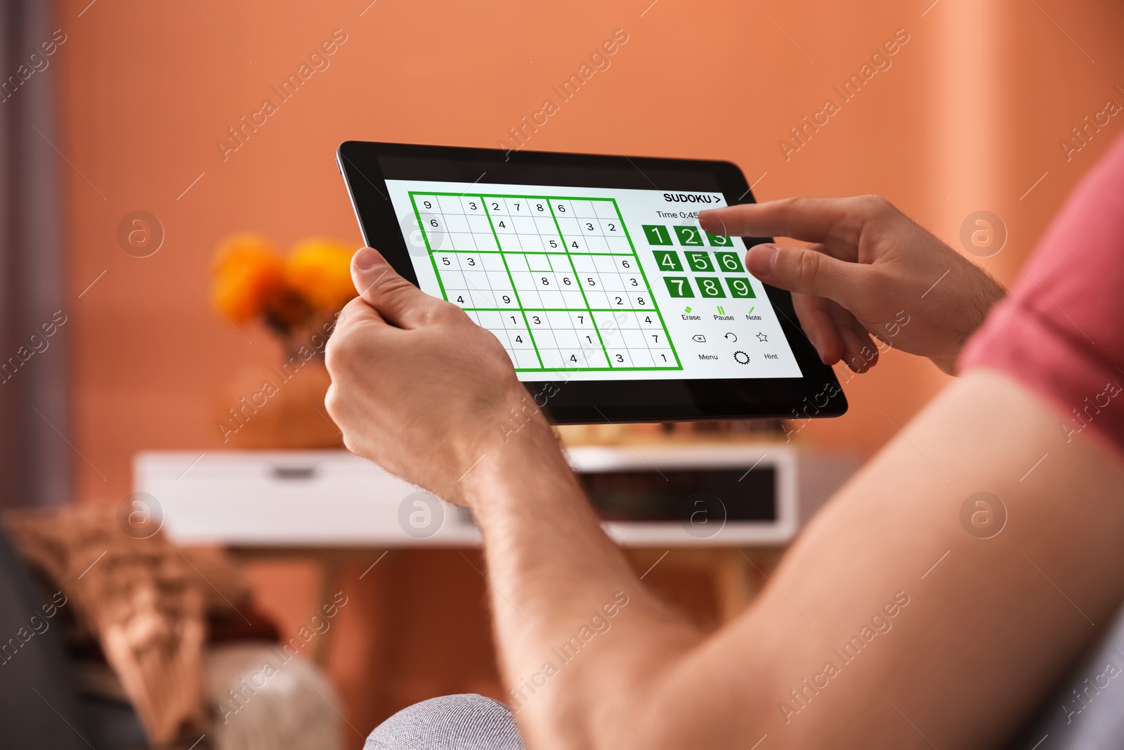 Image of Man playing sudoku game on tablet indoors, closeup