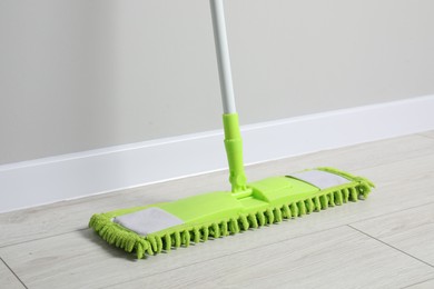 Mop with plastic handle near wall indoors