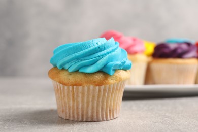 Photo of Delicious cupcakes with bright cream on gray table, selective focus