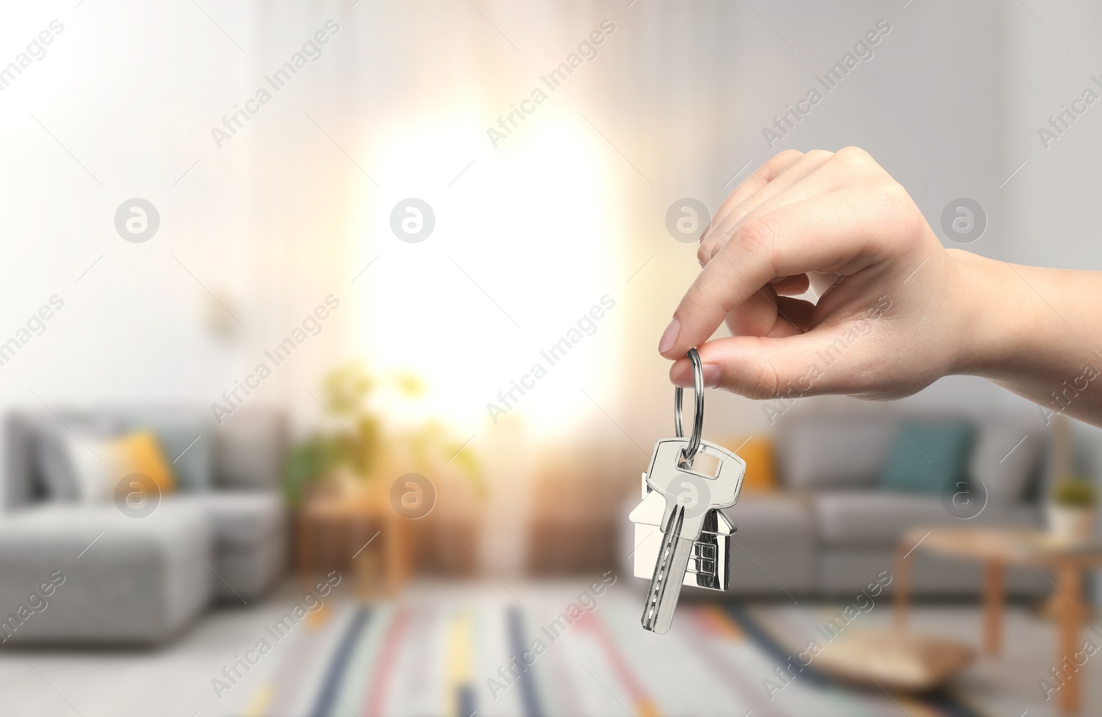 Image of Woman holding house key in room, closeup