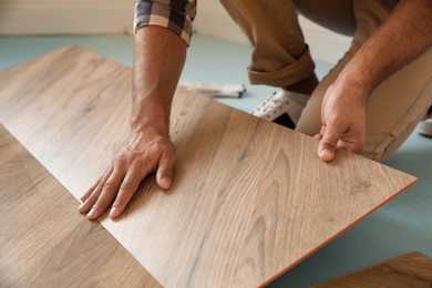 Professional worker installing new parquet flooring indoors, closeup